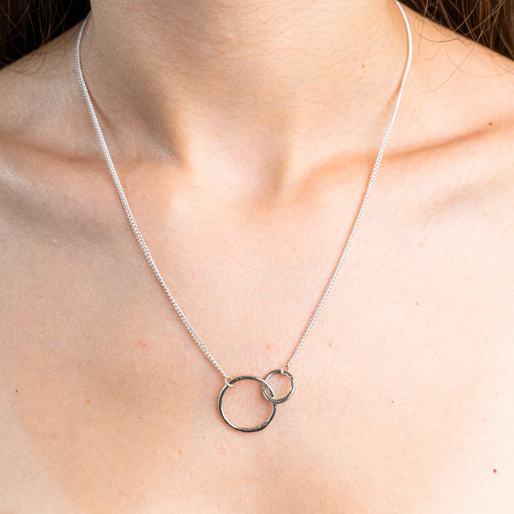 Sterling Silver Necklace with two interlocking circles.  One circle bigger then the other. Both circles textured with the hammered effect.