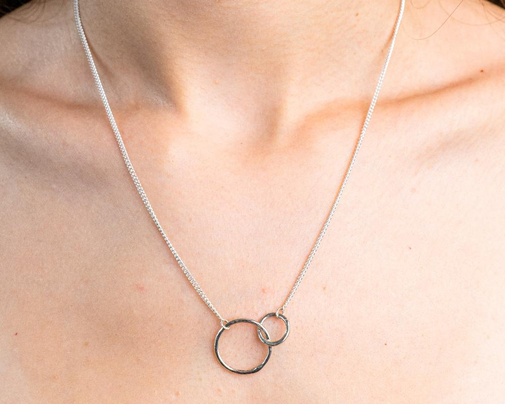 Sterling Silver Necklace with two interlocking circles.  One circle bigger then the other. Both circles textured with the hammered effect.