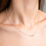 Sterling Silver Necklace with a infinity Style pendent with. Worn on a model with side profile.