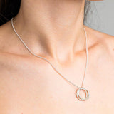 Sterling Silver Necklace with a intertwined Russian Ring Style pendent with a Hammered texture. Worn on a model with side profile.