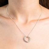 Sterling Silver Necklace with a intertwined Russian Ring Style pendent with a Hammered texture. Worn on a model with front profile.